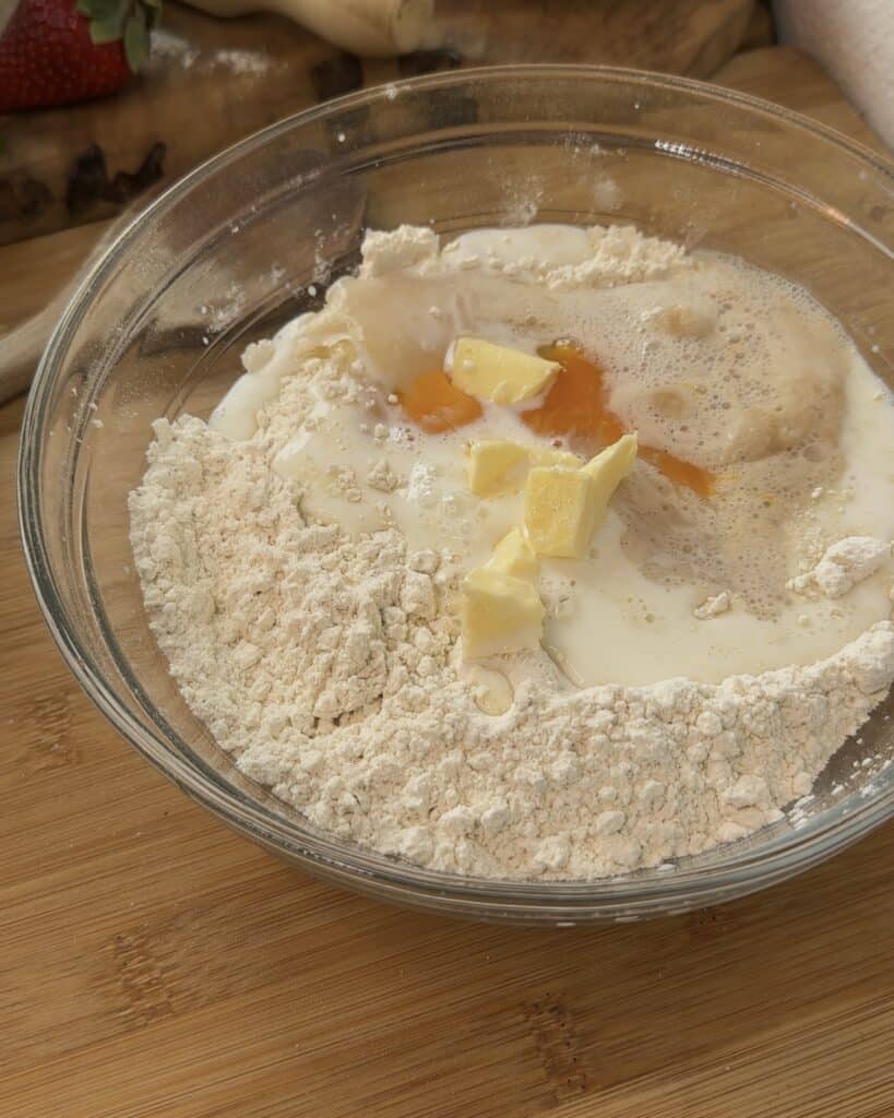 All the Nutella Bomb Donut dough ingredients before kneading, including flour, sugar, yeast mixture, milk, and butter, ready to be mixed into a soft, elastic dough.