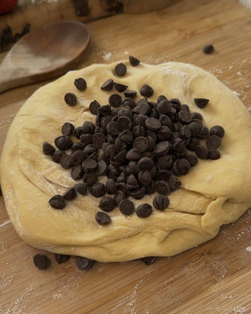 Proofed Nutella Bomb Donut dough with chocolate chips ready to be folded in, showing a soft, risen texture before shaping and frying.