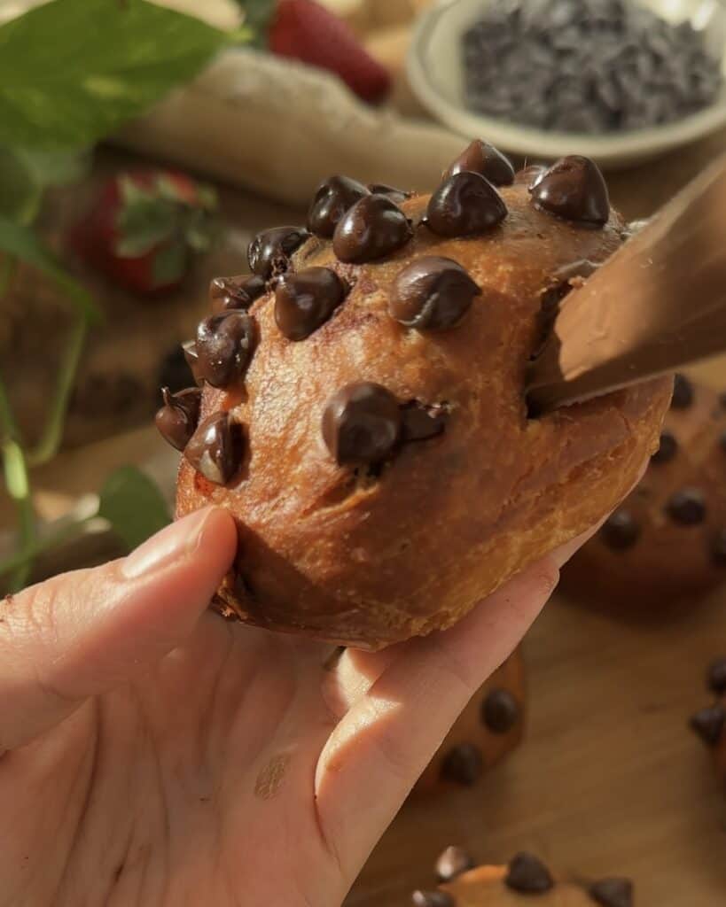 Filling Nutella Bomb Donuts with creamy Nutella using a piping bag, adding a rich, chocolate-hazelnut filling to the center of each soft, fluffy donut.