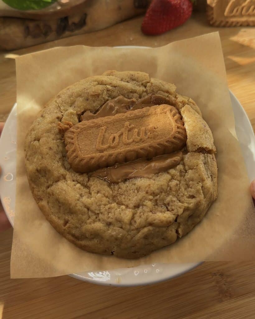 Image of a single-serve Biscoff stuffed cookie held in hand, showcasing the gooey Biscoff spread and marshmallow center, perfect for a delicious Biscoff marshmallow stuffed cookie experience.