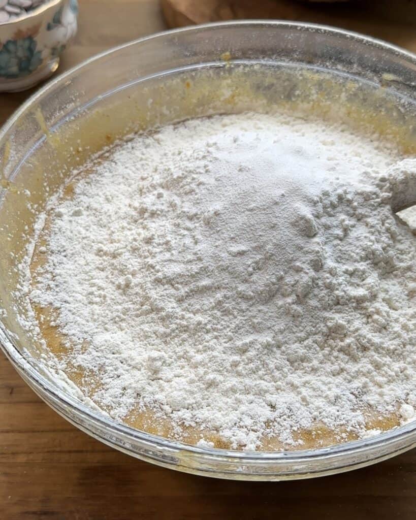 Close-up of a bowl with all ingredients mixed, but flour still visible on top