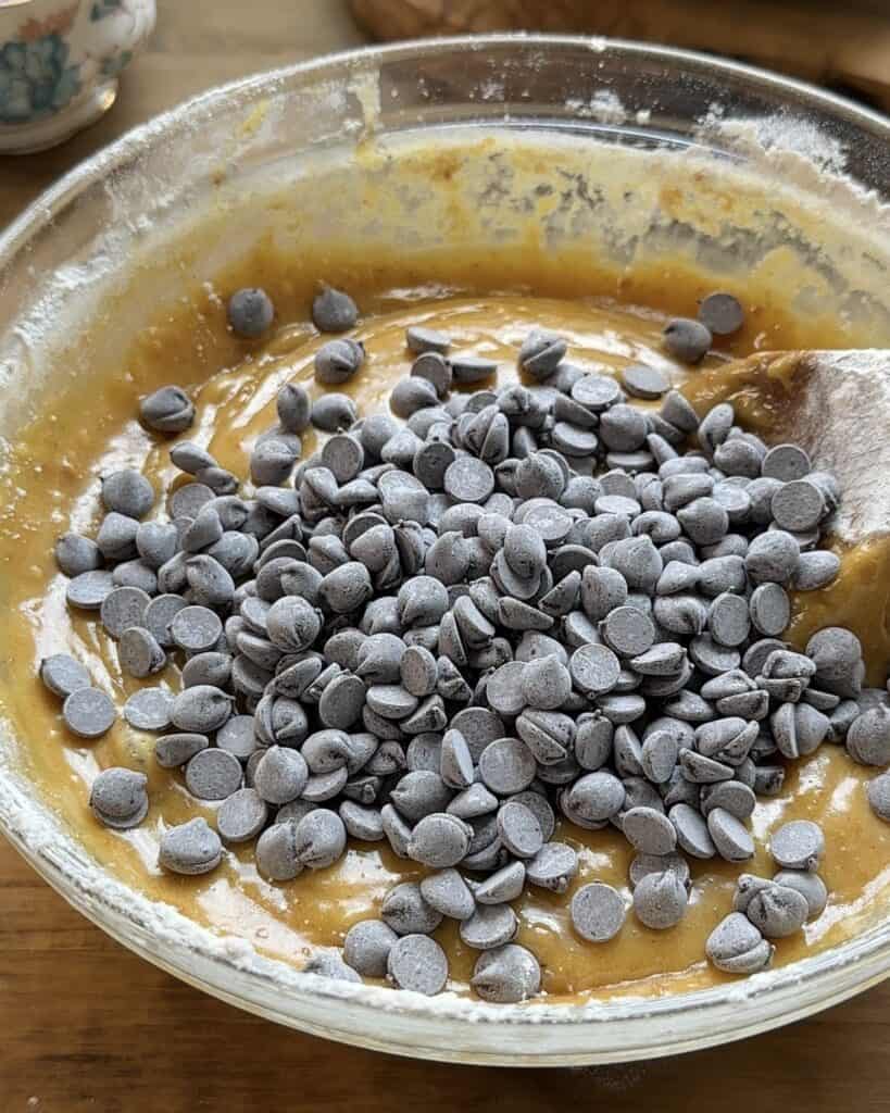 Unbaked cookie dough with chocolate chips on top, not yet mixed in, ready to be baked into a delicious treat.