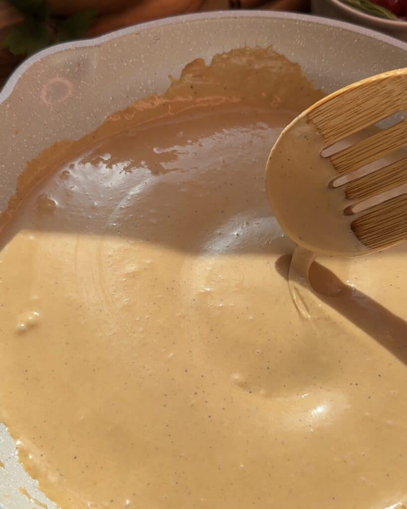 Smooth and creamy sauce simmering in a pan, with a rich and glossy texture.