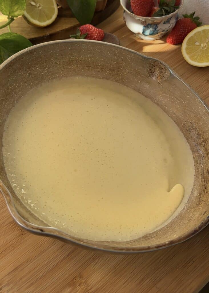 Tilting non-stick pan to spread crepe batter evenly for perfect thin crepes.