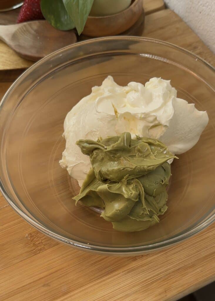 Creamy cream cheese and pistachio spread in a bowl, ready to be mixed for a smooth and delicious no-bake pistachio cheesecake filling.