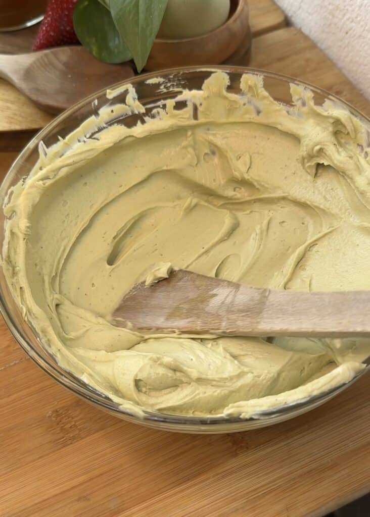 Creamy cream cheese and pistachio spread mixed in a bowl, creating a rich and smooth filling for a no-bake pistachio cheesecake.