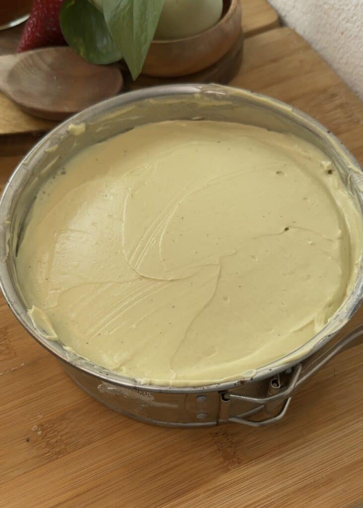 No-bake pistachio cheesecake with a smooth creamy filling on a crunchy crust, ready to be refrigerated and set.