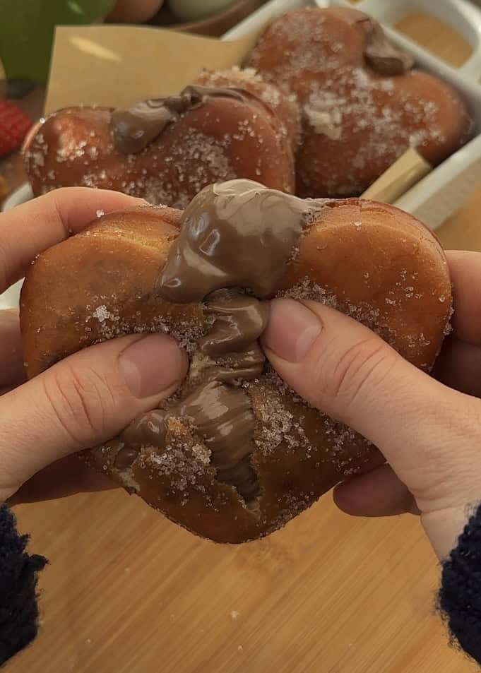 Heart-shaped Nutella donut cut in half, showing oozing Nutella filling and fluffy texture.