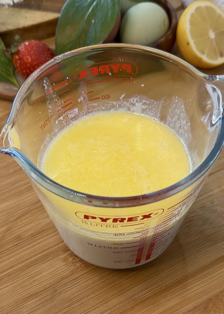 A separate bowl with wet ingredients for Nutella crepe rolls: melted butter, eggs, and warm milk ready to be mixed