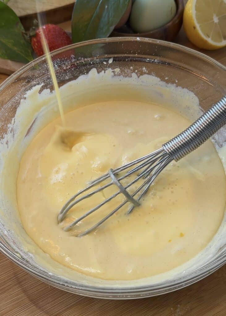 Mixing the crepe batter in a bowl for making Nutella crepe rolls, combining dry and wet ingredients.