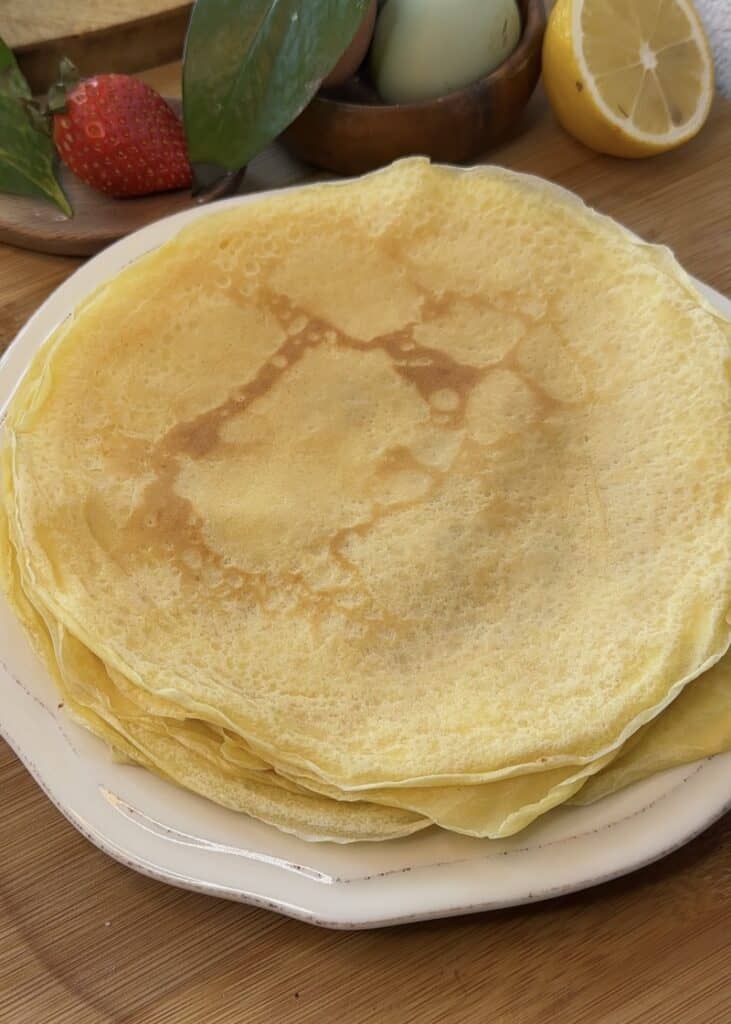 Stack of cooked crepes on a plate, ready to be filled with Nutella for Nutella crepe rolls