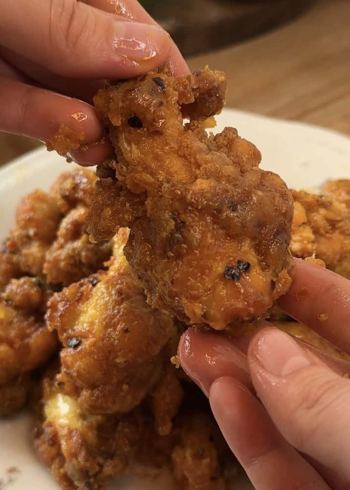 A perfectly golden-brown, crispy, and juicy chicken drumstick coated in a rich garlic Parmesan butter sauce.