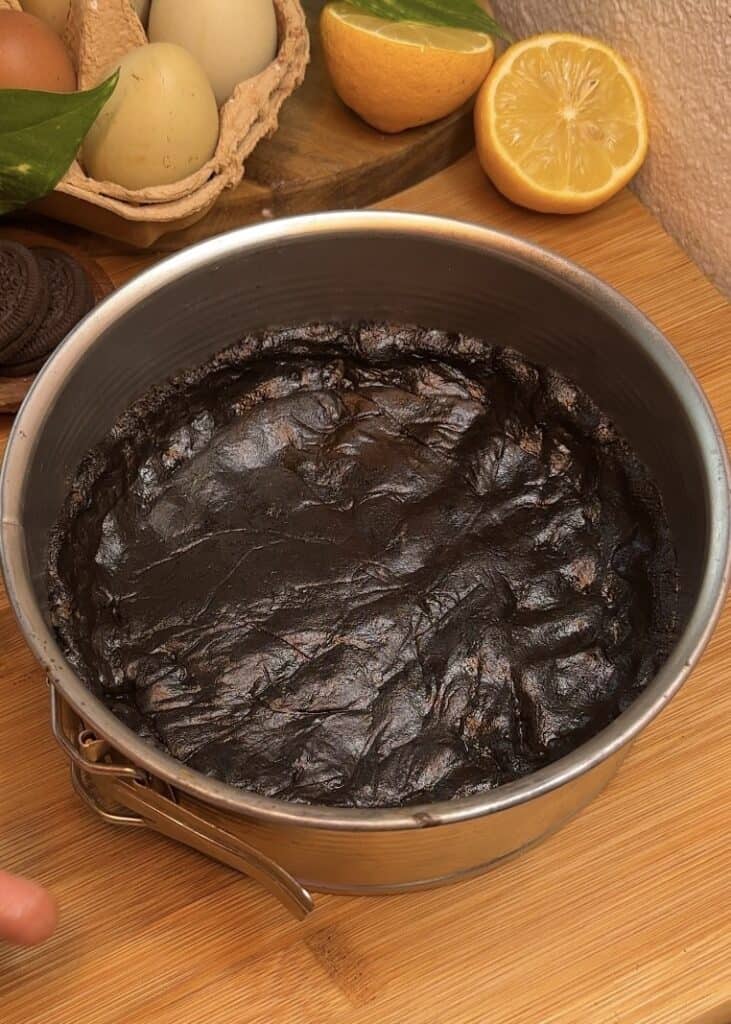 Oreo crust in the base of a mold for no-bake chocolate Oreo cheesecake, made by mixing crushed Oreo cookies and butter, then pressing it into a greased mold.