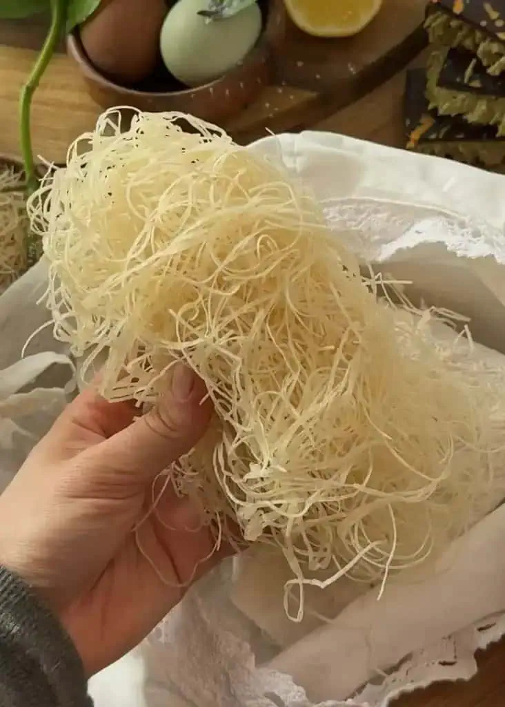 Hand holding a stack of freshly made homemade kataifi pastry, perfect for Dubai chocolate desserts