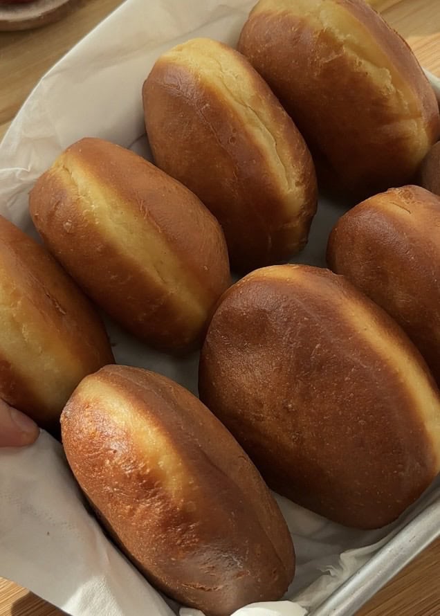 Freshly fried donuts placed on paper towels to absorb excess oil, for making easy strawberry cheesecake stuffed donuts.