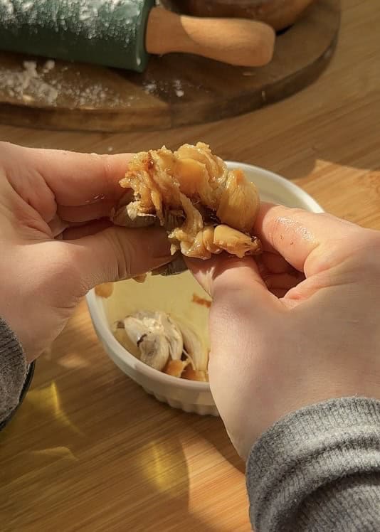 Close-up of creamy garlic cloves confited in oil, showing the soft interior to prepare garlic butter filling for buttery cheese garlic rolls.