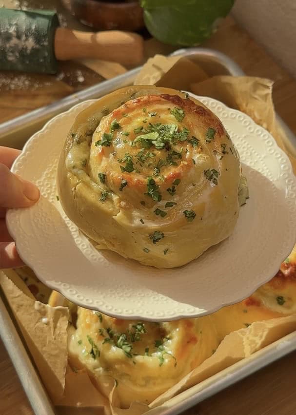 A buttery cheese garlic roll on a plate, soft, fluffy, and filled with melted, bubbly mozzarella cheese and rich garlic butter inside.