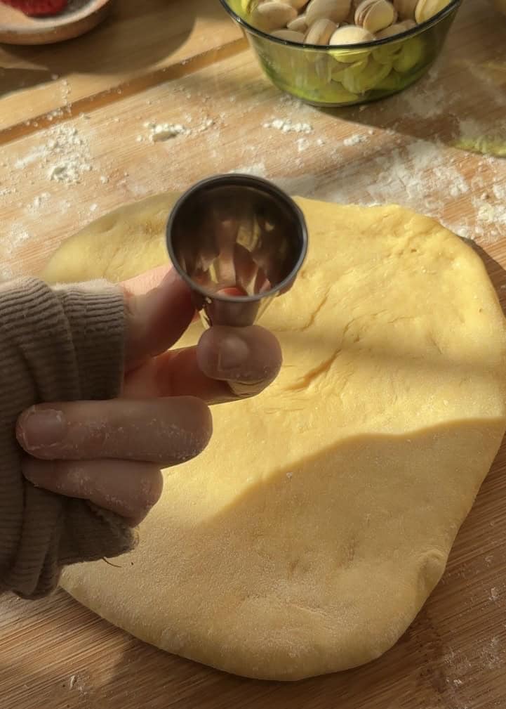 Shaping donut holes using the large hole of a sleeve cone, ready to be fried and transformed into golden brown Pistachio Donut Holes with pistachio butter glaze and crunchy toppings