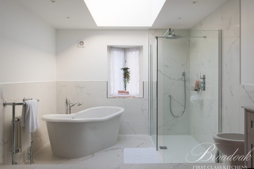 Contemporary white bathroom with marble accents, free-standing bathtub, walk-in shower, and modern fixtures, showcasing luxury bathroom design by Broadoak Kitchens Ltd.