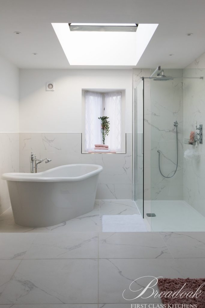 Bright modern bathroom with a freestanding bathtub, walk-in shower, marble tiles, and a skylight, showcasing premium bathroom and kitchen renovation services by Broadoak Kitchens Ltd.
