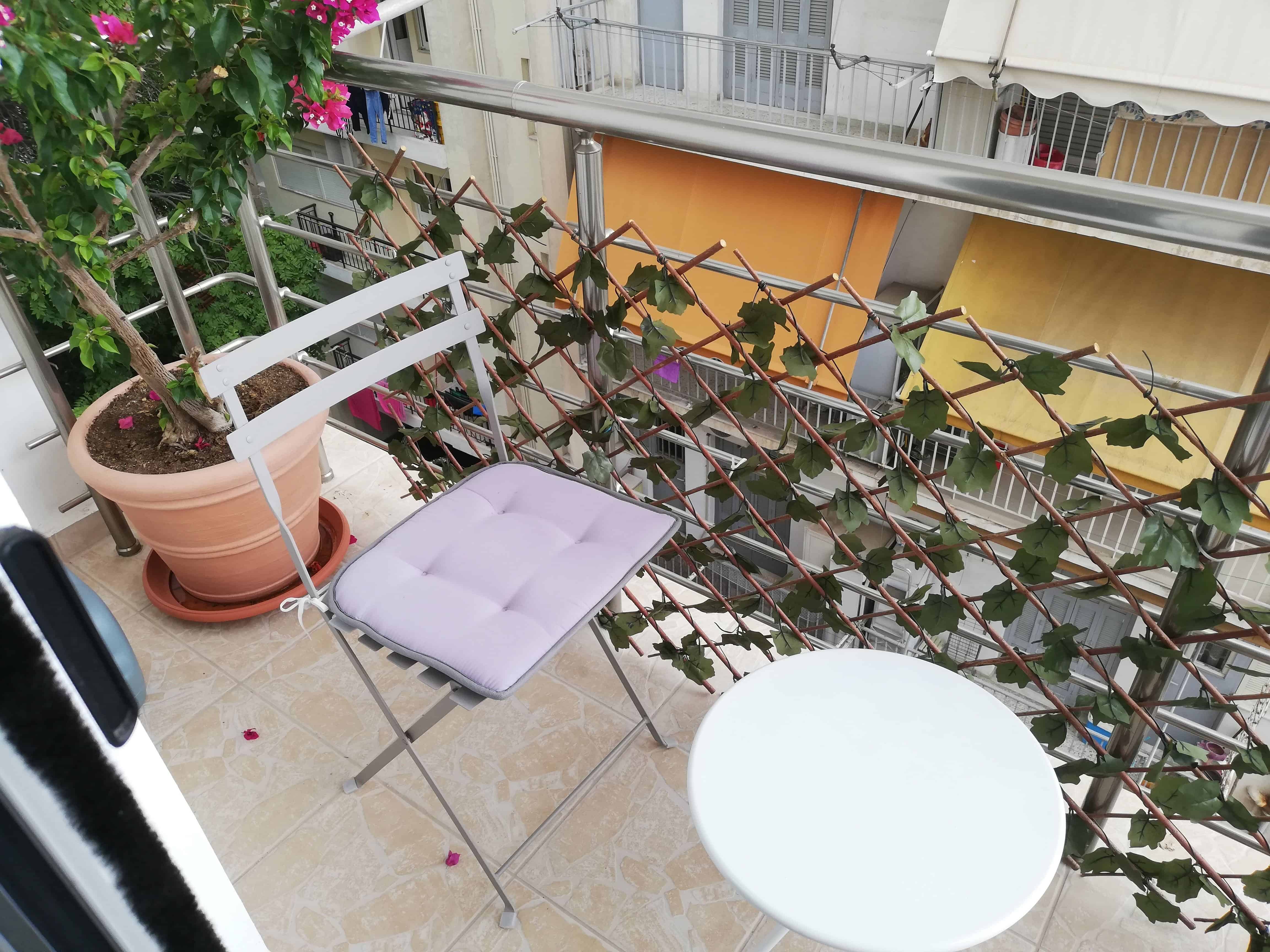 Apartment balcony with table and two chairs.