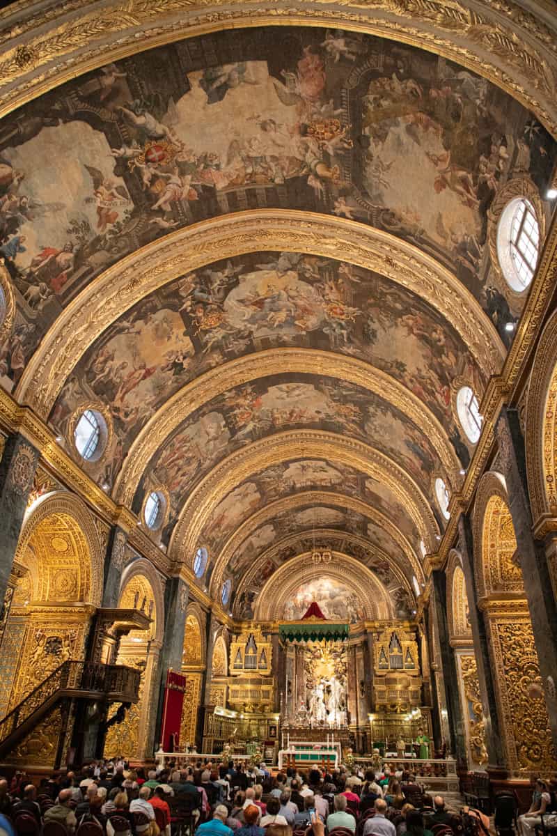 Intricate baroque church interior with gilded arches and detailed ceiling frescoes.