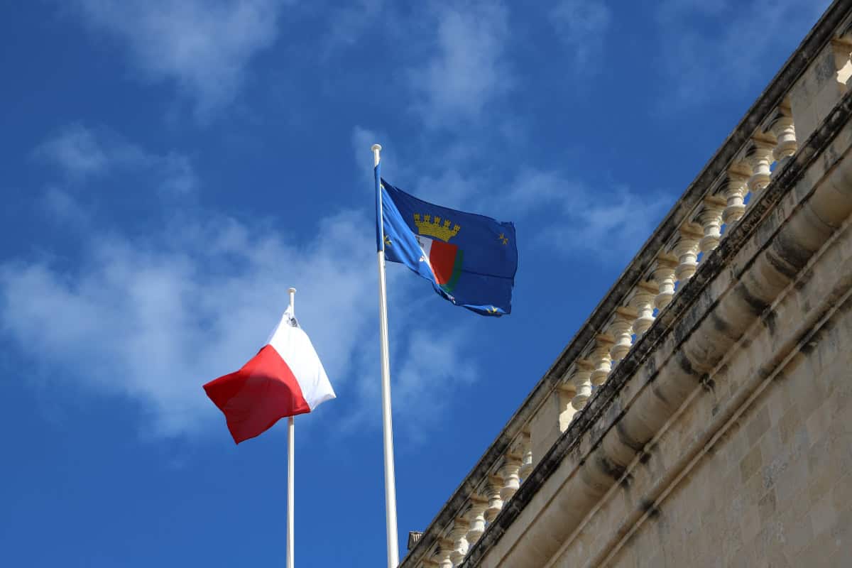 French and European flags flying outside historic building in France, symbolising national pride and heritage.