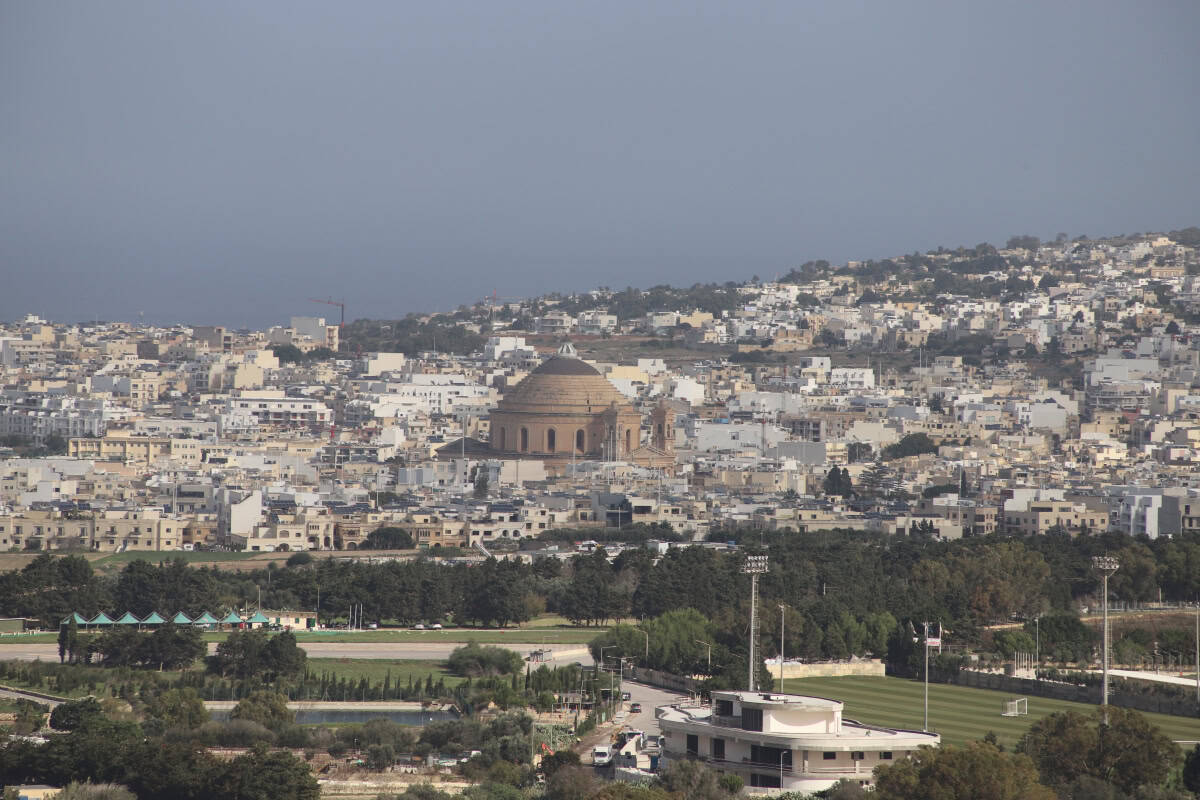 Historic building in the city, surrounded by white residential areas, hills and lush green parks in the background.