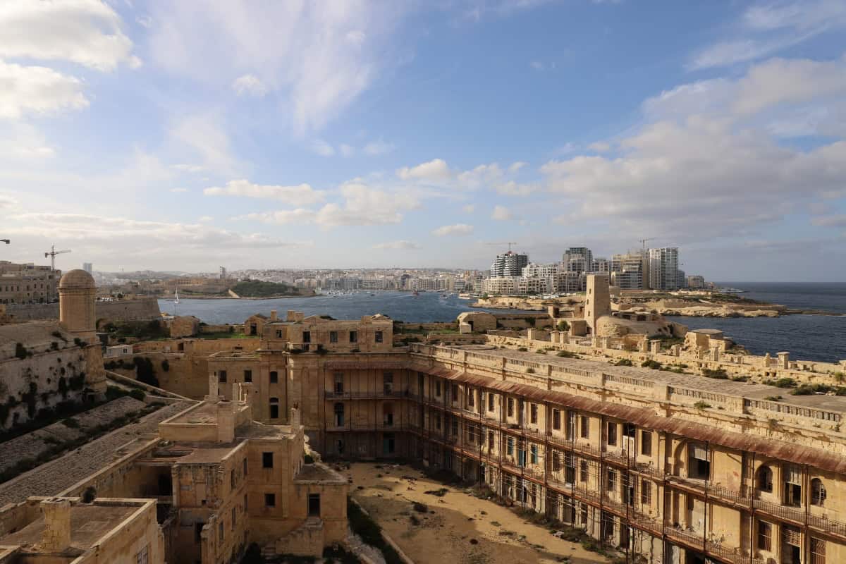 Historic fortress overlooking modern cityscape on the Maltese coastline.