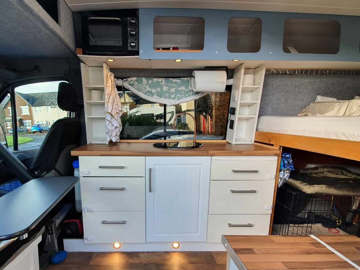Cozy camper van interior with compact kitchen and sleeping area, perfect for vanlife adventures in the UK.