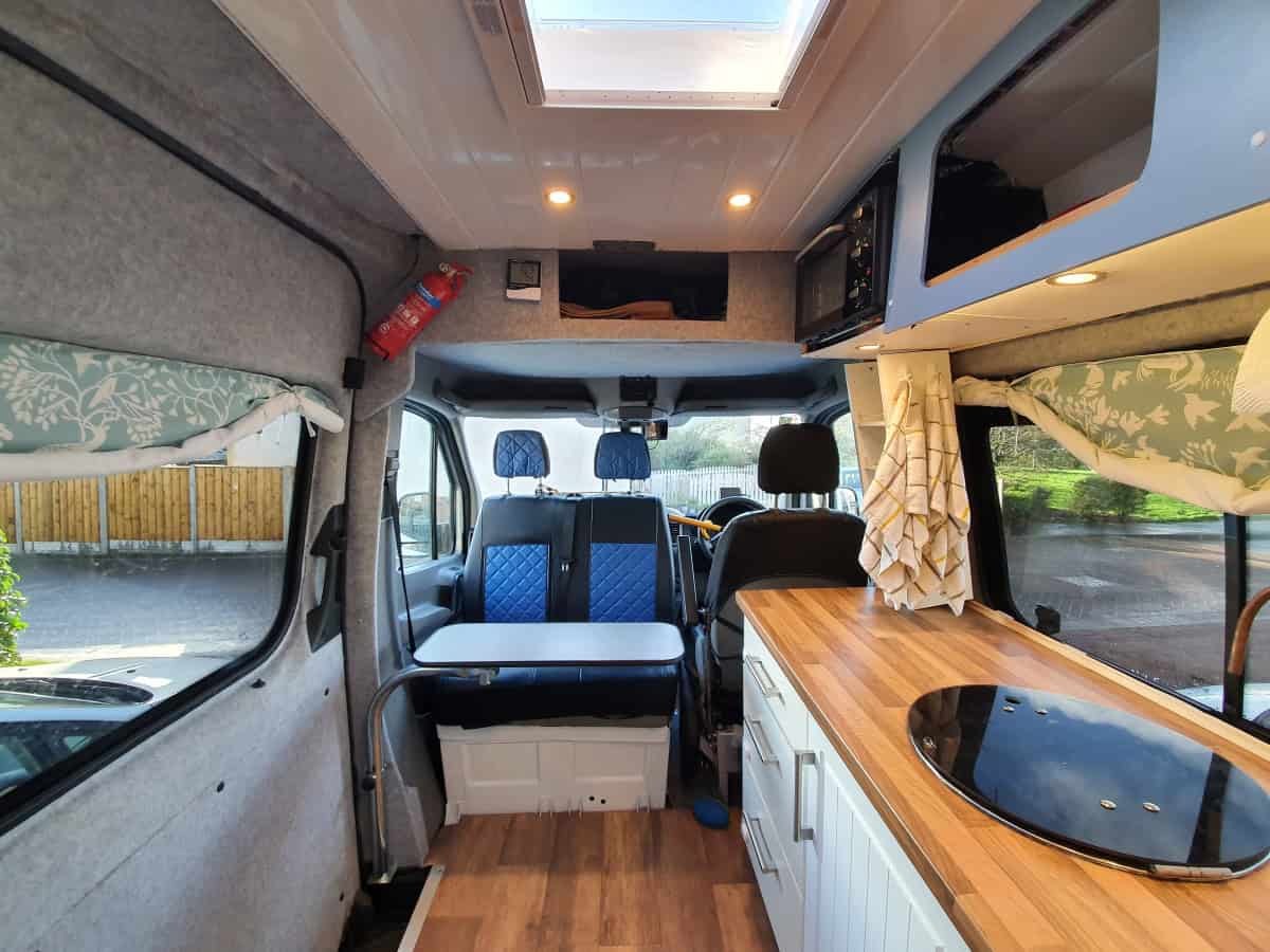 Cozy camper van interior with compact kitchen and seating area, perfect for van life adventures.