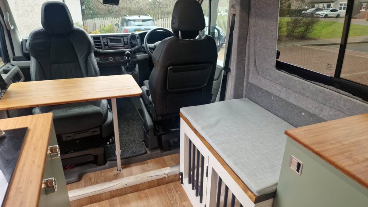 Cozy van interior with wooden tables and seating, perfect for van life adventures and travel exploration.