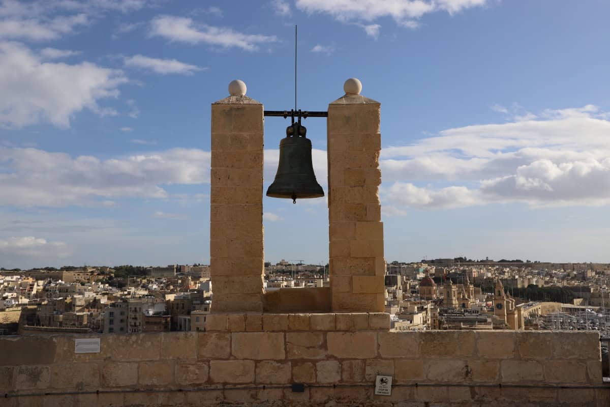 Bell atop historic tower with cityscape view in Malta.