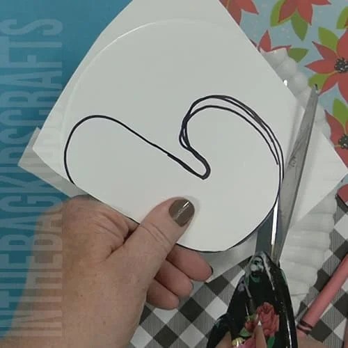 A colorful Christmas craft featuring a simple candy cane craft, perfect as an easy craft for kids during the holiday season. Step 2 cutting out the candy cane.