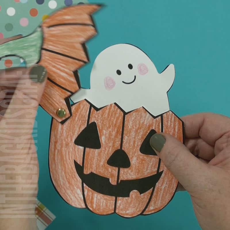 An image depicting a jack-o-lantern craft for kids, featuring a printable ghost template as part of a Halloween-themed activity.