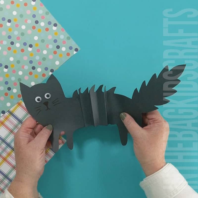 An image showing a paper black cat craft for kids, perfect for a simple Halloween craft and fall activity.
