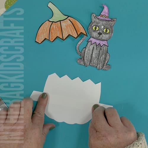 An image showing a Halloween craft for kids featuring a pumpkin craft and black cat craft, using a Halloween printable template. step 3