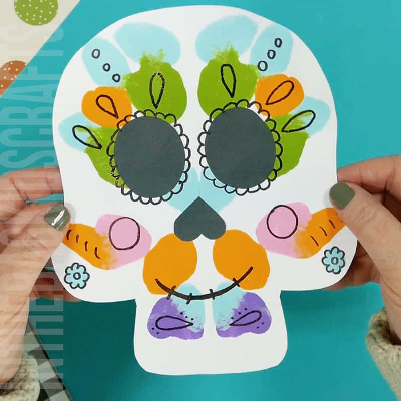 An image showing a colorful paper skull craft for kids, perfect as a Day of the Dead craft activity.