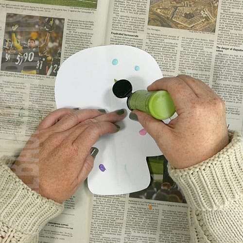 An image showing a colorful paper skull craft for kids, perfect as a Day of the Dead craft activity.  day of the dead skull craft step 2 adding paint dots 