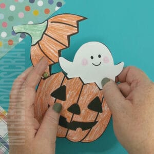 An image depicting a jack-o-lantern craft for kids, featuring a printable ghost template as part of a Halloween-themed activity.