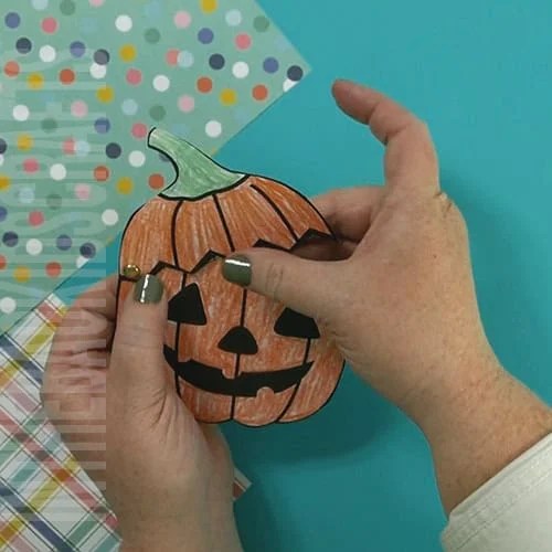 adding the brad to the jack-o-lantern so that the top opens on a hinge 