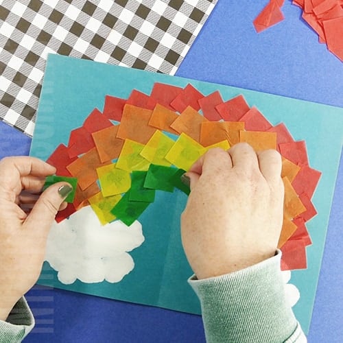 Rainbow craft for kids step 6 made with painted clouds and tissue paper square for colors or rainbow 
