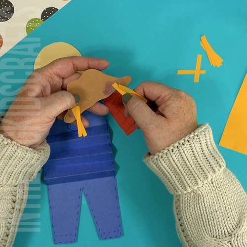 An image showing a paper scarecrow craft, perfect as an easy fall craft for kids to enjoy making.