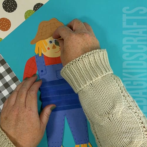 An image showing a paper scarecrow craft, perfect as an easy fall craft for kids to enjoy making.