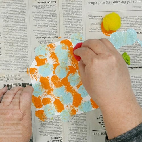 Colorful turkey craft for kids featuring a free turkey outline, ideal as a Thanksgiving craft for preschool and kindergarten children. pompom painting