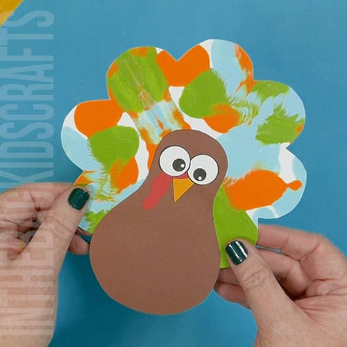 Colorful turkey craft for kids featuring a free turkey outline, ideal as a Thanksgiving craft for preschool and kindergarten children. squish painted feathers turkey art