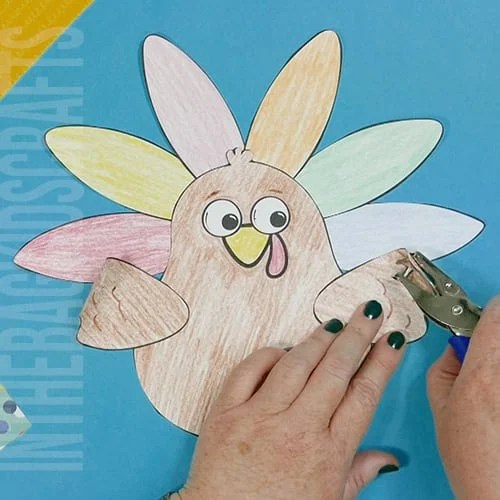 A colorful, kid-friendly turkey craft for Thanksgiving featuring a free printable template, perfect for a gratitude-themed craft for kids. step 5 punch the holes