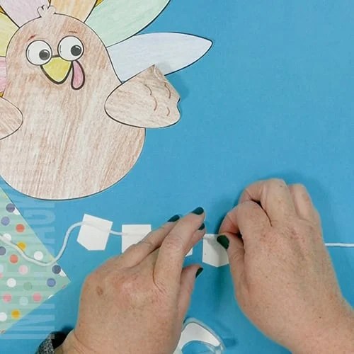 A colorful, kid-friendly turkey craft for Thanksgiving featuring a free printable template, perfect for a gratitude-themed craft for kids. step 6 putting together the thanks banner