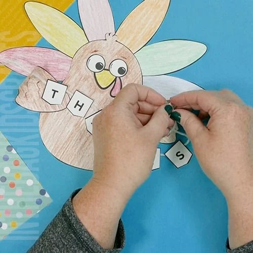 A colorful, kid-friendly turkey craft for Thanksgiving featuring a free printable template, perfect for a gratitude-themed craft for kids. step 7 adding the thanks banner to the turkey