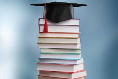 Stack of colorful books with graduation cap, symbolizing education and learning.